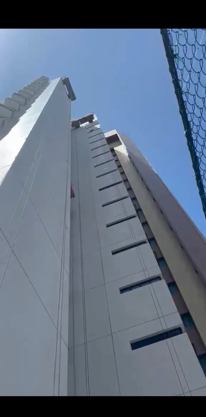 Dois alpinistas industriais fazendo pintura predial na fachada